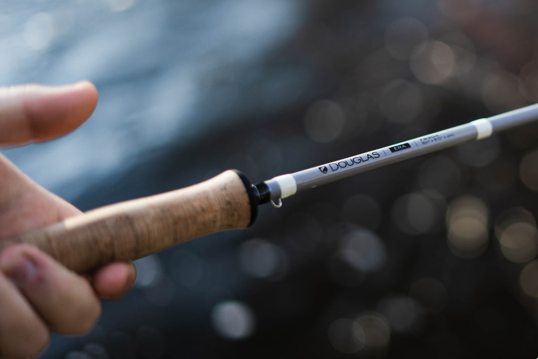 Close-up of a hand on the cork grip of a Douglas ERA fly rod over water
