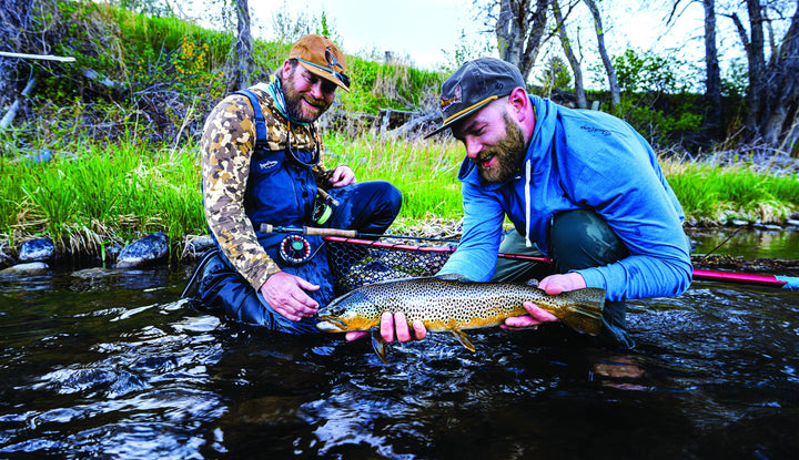 Two anglers releasing a brown trout caught on a Douglas DXF Gen 2