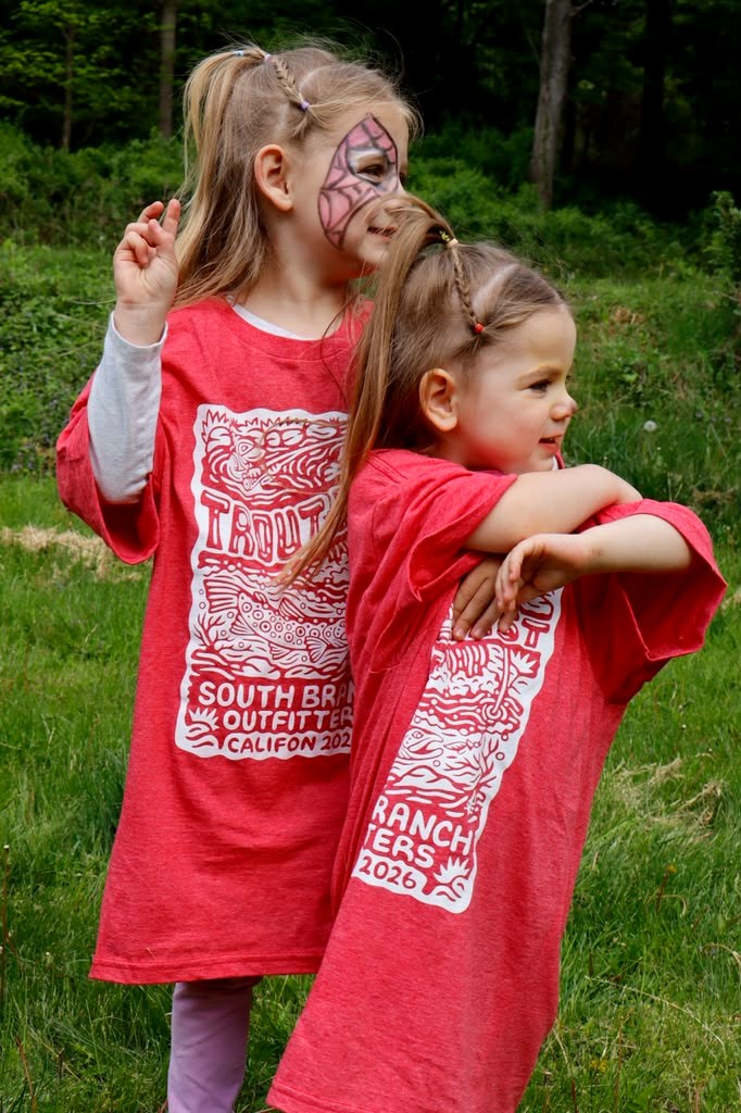 Two young sisters in Trout Fest t-shirts, one with face paint