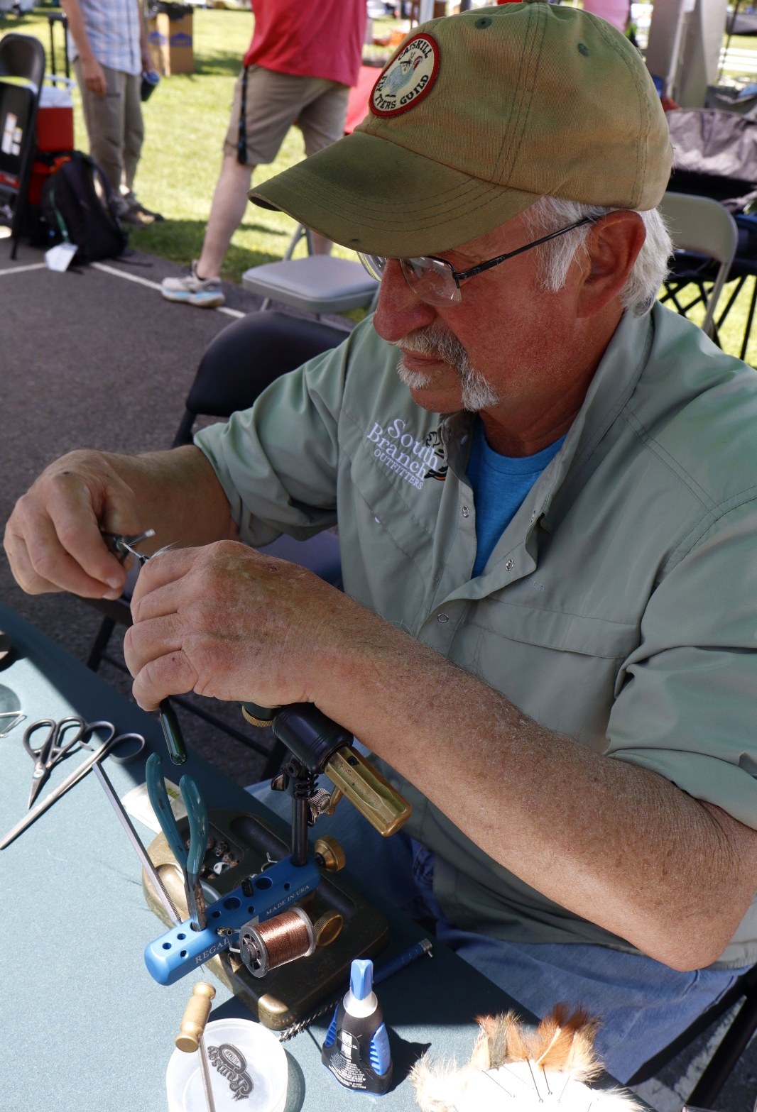 A tyer at the vise during a fly tying demo at Trout Fest